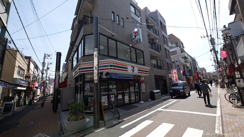 Wide-angle shot of two narrow streets with a Seven Eleven on the corner