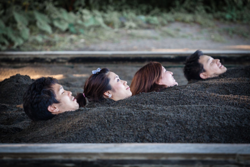 Four people buried in black sand up to the neck