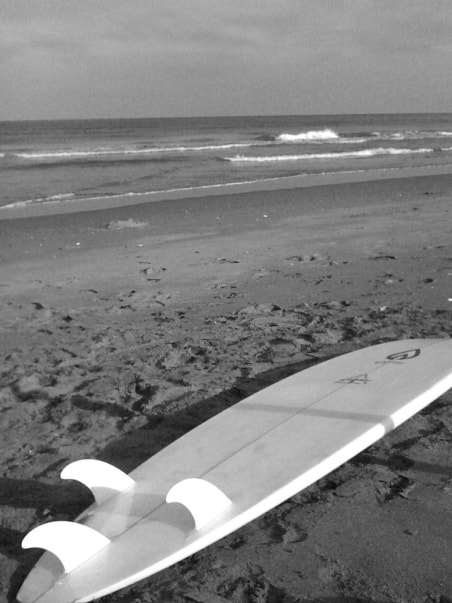 Black and white photo of a surfboard on a beach
