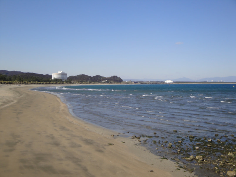 An empty beach and shoreline, with a resort in the distance