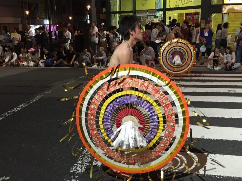 Man participating in festival with large paper and bamboo umbrella