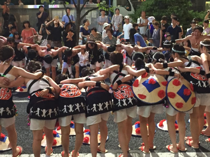 The Yamagata University troupe huddles before the parade starts as the crowd eagerly awaits