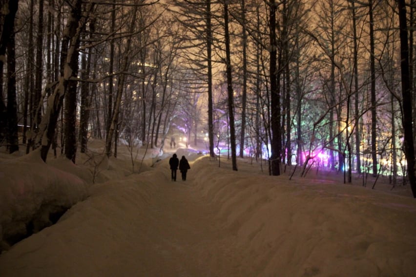 A couple walks from Mori no Tokee to Furano Kankanmura on the path down the hill from Ningle Terrace