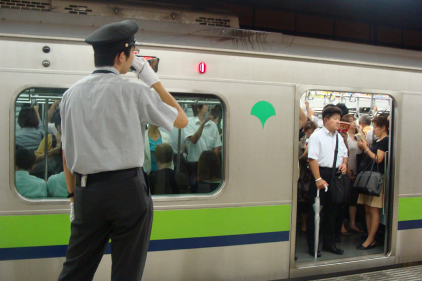A station attendant blows his whistle as a train gets ready to leave